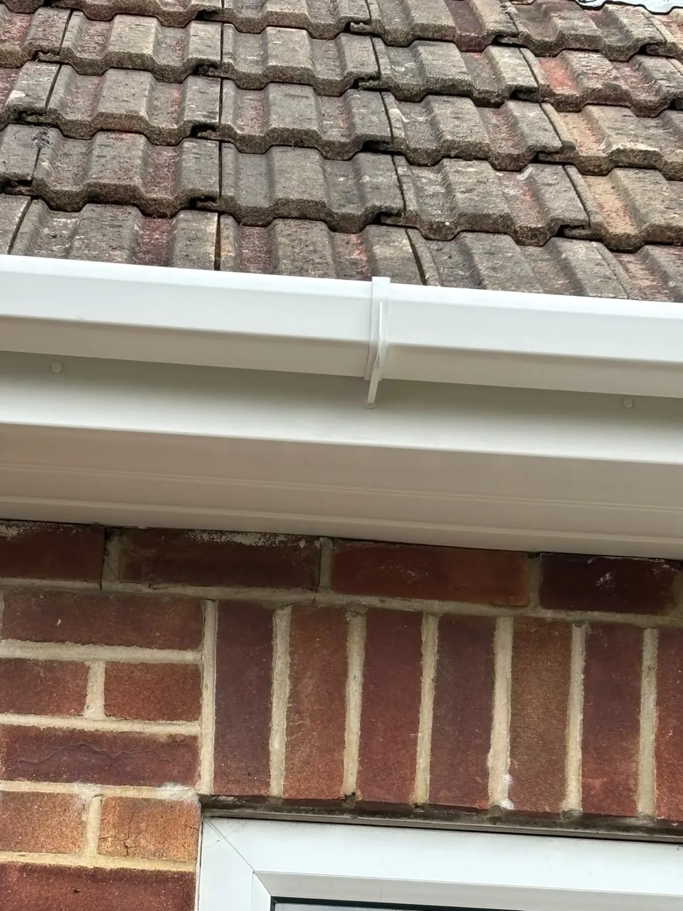 White uPVC guttering fitted above brickwork and window
