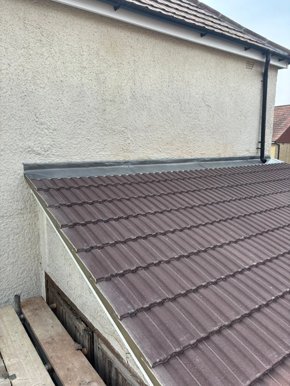 Lead flashing along the wall junction of a tiled lean-to roof