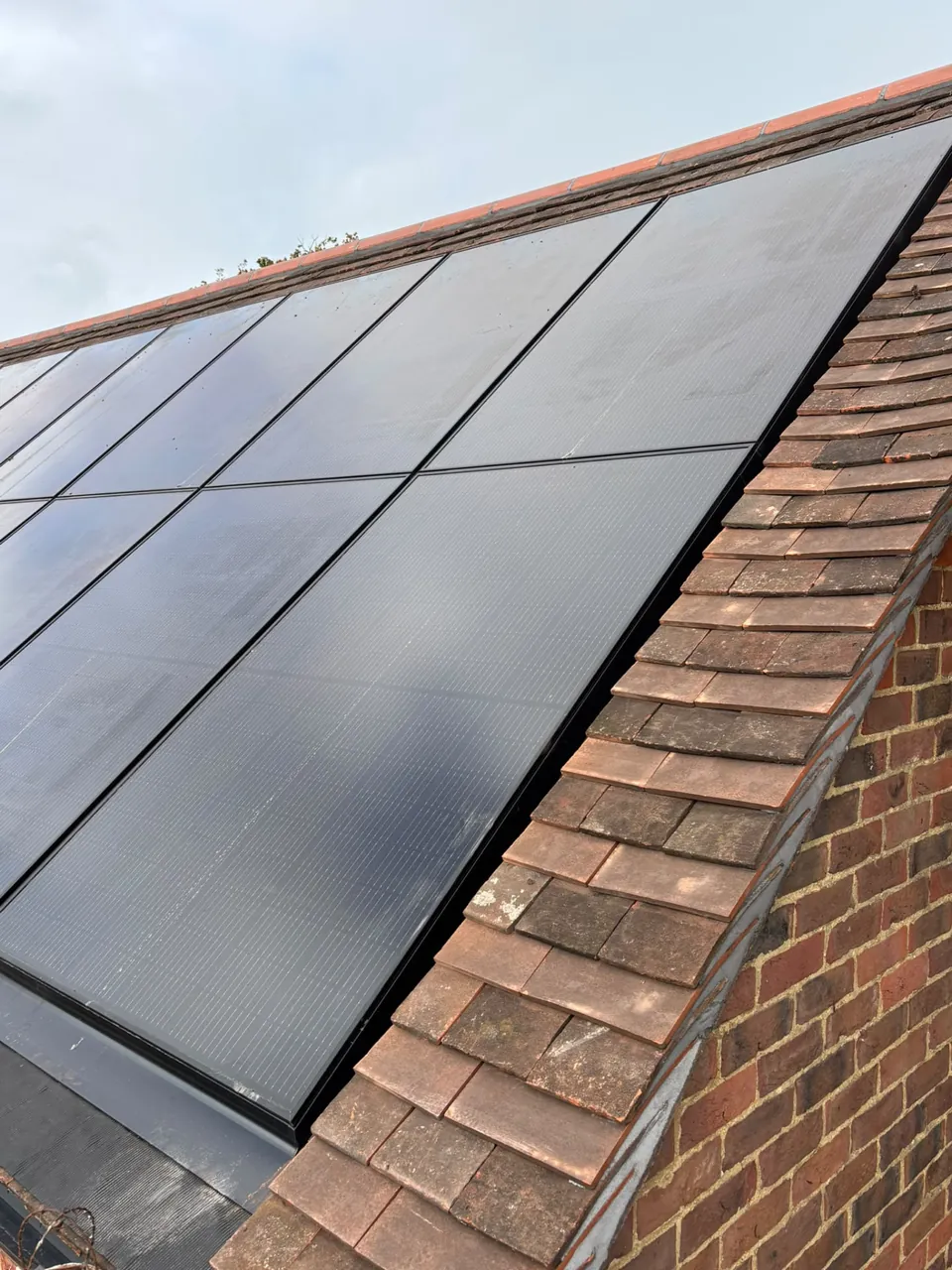 Tiled roof and verge beside a brick gable with solar panels